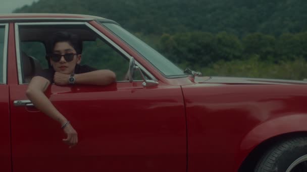 一个残忍的假小子女孩坐在一辆老式红色汽车上的肖像 高质量的4K镜头 — 图库视频影像