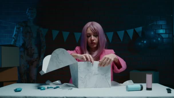 坐在桌旁 穿着粉红夹克化着妆的悲哀的粉红头发的生日女孩 在一间装饰着生日装饰品的黑暗的房间里吃着生日蛋糕 高质量的4K镜头 — 图库视频影像