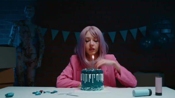 悲伤的粉红头发的生日女孩 化着妆 泪汪汪的眼睛 穿着粉红的运动衫坐在桌旁 用蓝色的生日蛋糕哭着 生日那天在一间黑暗的房间里点着蜡烛 — 图库视频影像