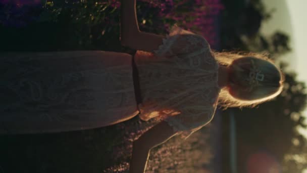 金色的金发女子穿着白色花边裙 在美丽的紫罗兰花田里 金色的时辰从后面走过 夏天的概念 大自然 野生野花 有毒植物 德尔菲 — 图库视频影像