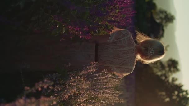 레이스 드레스에 여자는 시간에 화려한 보라색 꽃밭에서 뒤에서 자연의 야생화 — 비디오