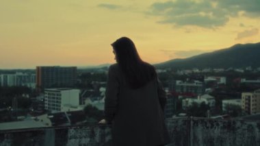 Dağ manzaralı, şehrin tepesine bakan esmer bir kızın sırtından çekilmiş yatay bir video. Özgürlük, gençlik konsepti 4K görüntüleri. Yüksek kalite 4k görüntü