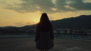 Gün batımına doğru yürüyen genç bir kızın yakın plan portresi. Dağ manzarası, özgürlük, gençlik konsepti 4K görüntüleriyle çatıda dönüyor. Yüksek kalite 4k görüntü