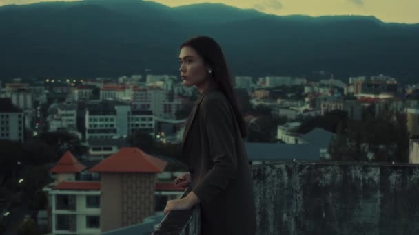 ブルネットの若い女の子の横のビデオは 山の景色を望む屋上に街の上を見下ろすスーツに似ています 街並みのコンセプト4K映像 高品質の4K映像 — ストック動画