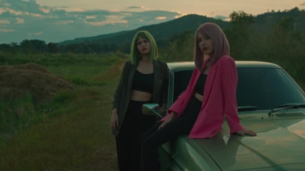 绿色头发的姑娘和她的红头发的女朋友坐在有山景的老式绿色轿车上 高质量的4K镜头 慢动作 — 图库视频影像
