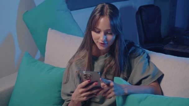 Kvinne Med Elektrisk Blå Telefon Sitter Rolig Sofa Smiler Mens – stockvideo