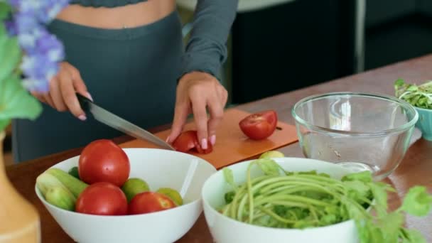 女性は レシピのための食材として新鮮な天然食品を使用してキッチンで料理を準備するために 切削板にトマトをスライスしています — ストック動画
