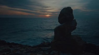 4K 'lık bir zaman kaydırağı günbatımının görüntüsü manzaralı, alışılmadık volkanik kaya oluşumları ve taşlı bir sahili olan bir deniz. Yüksek kalite 4k görüntü