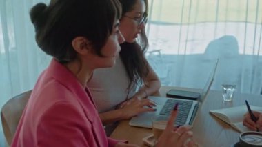 Modern uluslararası ofis. Kadınların iş buluşması. Üç kadın ortak çalışma alanında kahve ile fikirleri tartışıyor. İnsanlar masada oturuyor, beyin fırtınası yapıyor ve yaratıyorlar. Yüksek kalite 4k görüntü