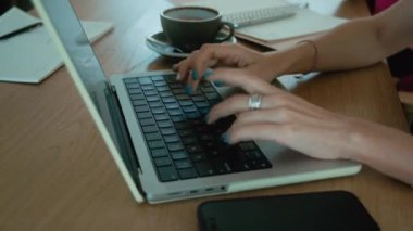 Dizüstü bilgisayar klavyesinde daktilo kullanan bir iş kadınının kadın elleri. Bilgisayarla, laptopla ve masada kahveyle çevrimiçi çalışıyorum. Yüksek kalite 4k görüntü