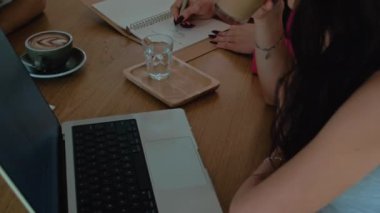 Modern uluslararası ofis. Kadın işleri, dizüstü bilgisayar ve kahveyle birlikte çalışma alanında buluşuyor. İnsanlar masada oturuyor, beyin fırtınası yapıyor ve yaratıyorlar. Yüksek kalite 4k görüntü