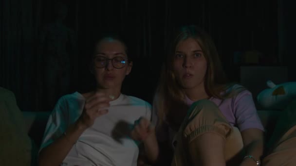 放大两个年轻女人的肖像 穿着睡衣坐在舒适的沙发上吃爆米花 晚上看恐怖片 恐惧的面部表情 滑行射击 高质量的 — 图库视频影像