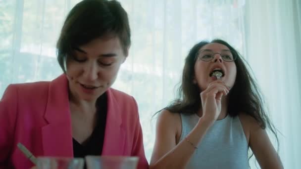 ウィメンズビジネスミーティング 2人の若い女性が手でメモを作り デザートを食べました コワーキングスペースのテーブル 高品質の4K映像 — ストック動画