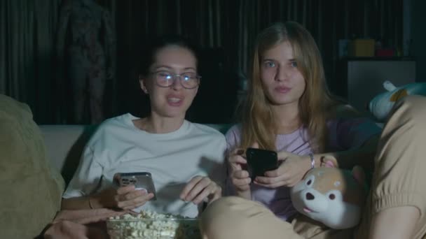Portrait Two Young Women Sitting Pajamas Phones Eating Popcorn Discussing — Stock Video