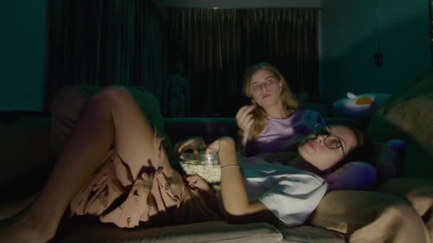 Two Young Women Lying Couch Eating Popcorn Pajamas Living Room — Stock Video