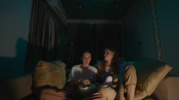 Young Woman Sitting Feeding Her Girlfriend Popcorn Pajamas Cozy Sofa — Stock Video