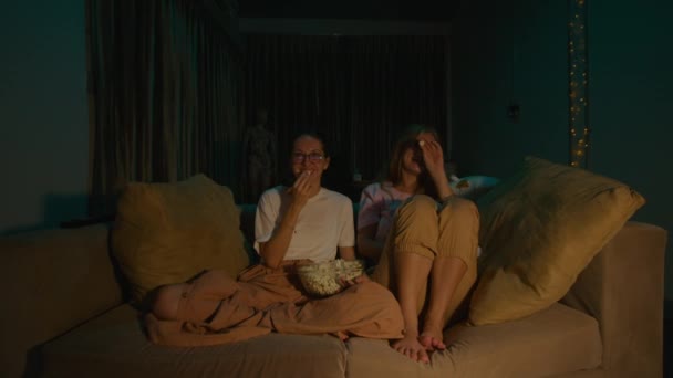 Powiększ Dwie Młode Kobiety Siedzące Jedzące Popcorn Piżamie Wygodnej Sofie — Wideo stockowe