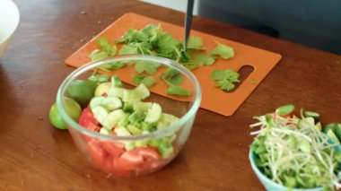 Bir insan, sebze kasesinin yanındaki kesme tahtasındaki yaprak sebzelerini keserek yemek için malzeme hazırlıyor.