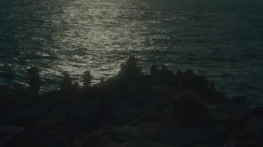 Bir 4K kaydırak görüntüsü, alışılmadık volkanik kaya oluşumları ve günbatımı dalgaları bir uçurumun kenarından görülüyor. Yüksek kalite 4k görüntü