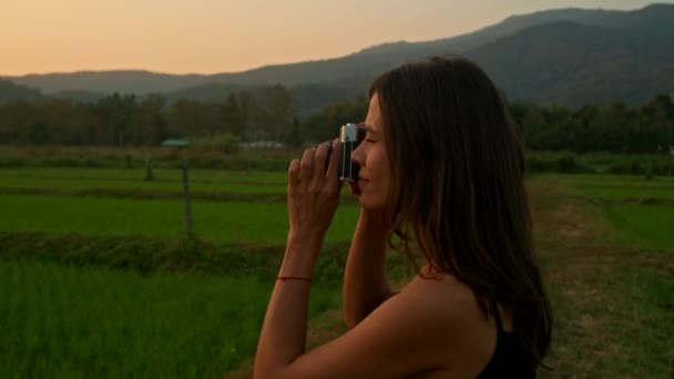 若い女性は 夏の日に山の背景を持つ田舎の古いカメラで写真を撮ります レトロカメラ レジャー活動 高品質の4K映像 — ストック動画