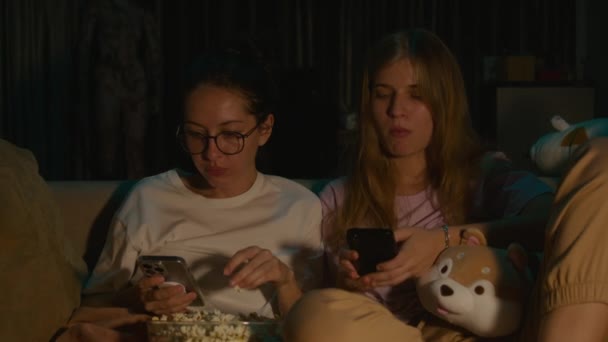 Portrait Two Young Women Sitting Pajamas Phones Eating Popcorn Watching — Stock Video
