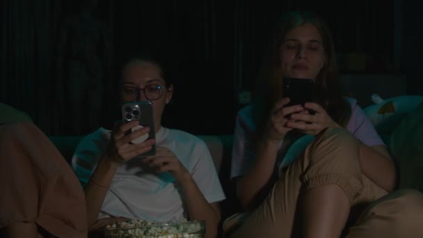 Портрет Двух Молодых Женщин Сидящих Своих Телефонах Поедающих Попкорн Пижаме — стоковое видео