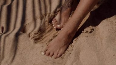 Sahilde ıslak kuma batan ve arka planda su parıldayan, huzur ve rahatlama ve dinlenme için mükemmel bir görüntü yaratan bir insan ayağı.