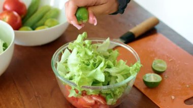 Lezzetli bir tarifte malzeme olarak kullanılmaya hazır, ahşap bir masanın üzerinde bir tabak yeşil marul ve sulu domates.