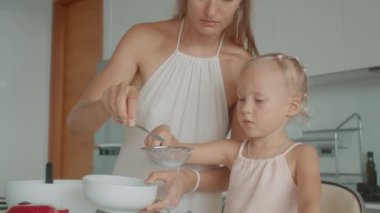 Anne ve kızı beyaz bir mutfakta birlikte waffle yapıyorlar.