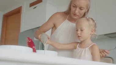 Anne ve kızı beyaz bir mutfakta birlikte waffle yapıyorlar.