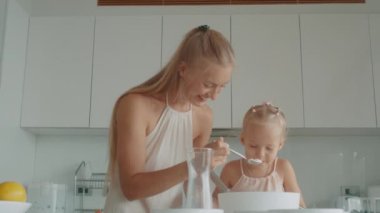 Anne ve kızı beyaz bir mutfakta birlikte waffle yapıyorlar.
