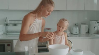 Anne ve kızı beyaz bir mutfakta birlikte waffle yapıyorlar.