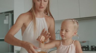 Anne ve kızı beyaz bir mutfakta birlikte waffle yapıyorlar.