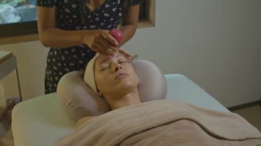 Bir kadın, sakin bir kaplıca ortamında güzel bir cilde sahip olmak için vakum cihazıyla yüz bakımı yaptırıyor.