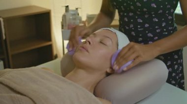 Bir insan, profesyonel güzellik ve cilt terapisinden yararlanarak spa 'da yatıştırıcı bir yüz tedavisi görüyor.
