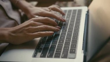 Dizüstü bilgisayarda yazı yazan ellerin yakınlaşması, sakin bir açık hava ortamında odaklanmış verimliliği gösteriyor, doğal ortam