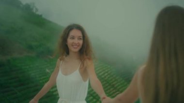 İki neşeli kadın güzel, sisli bir arazide birlikte oynayıp gerçek neşe ve dostluğu simgeliyor.