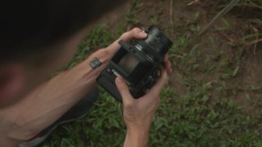 Klasik bir orta sınıf film kamerasını tutan ellerin yakın plan görüntüsü, doğanın güzelliğini mercekten gösteriyor..