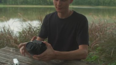 Klasik bir analog kamera, sade ve sade bir açık hava ortamında, ahşap bir masaya sıkıca tutunur.