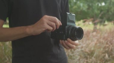 Hevesli ve kendini adamış bir fotoğrafçı, nefes kesici manzaraları çekmeye hazır orta formatlı bir film kamerasını sıkıca kavrıyor.