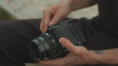 Bir insan klasik fotoğraf makinesi için titizlikle bir film rulosu hazırlar, analog fotoğrafçılığın gerçek özünü yakalar.