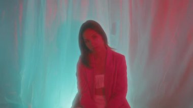 Göz kamaştırıcı bir modelin büyüleyici bir portresi. Canlı neon ışıklarla aydınlatılmış. Yumuşak, rüya gibi bir arka plana karşı.