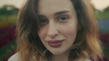 Gün batımında canlı çiçeklerle çevrili güzel bir genç kadının huzurlu bir portresi.