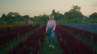Harika bir günbatımında, etrafında taze çiçeklerle çevrili harika bir süper 8 kameralı güzel bir genç kadının sakin portresi.