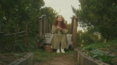 Kızıl saçlı genç bir kadın portakal bahçesindeki ahşap bir köprüde oturmuş portakal soyuyordu. 