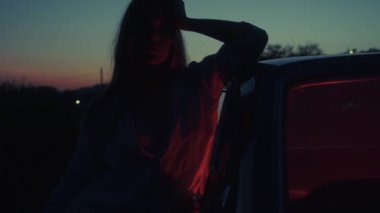 Sinematik çekim, kırmızı ışığı olan eski bir arabanın yanında duran bir kız. 