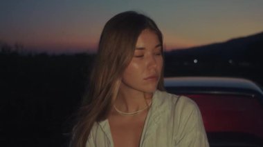 Sinematik çekim, kırmızı ışığı olan eski bir arabanın yanında duran bir kız. 