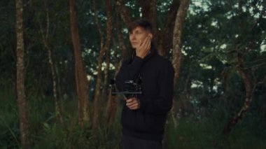 Genç bir adam, dingin bir ormanda mikrofonla çeşitli doğal sesleri hevesle yakalıyor.