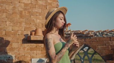 Benekli elbiseli, güneş gözlüklü, dezenyum tarlasında mor çiçekleri koklayan ve dokunan genç bir kadın. Doğayı seviyorum. Provence, yaz, tatil. Çiçek tarlasında genç bir kadın. Yakın plan.