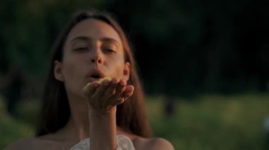 Huzurlu bir kız gökyüzüne renkli çiçek yaprakları salıyor, bahar boyunca doğada neşeli bir anı yakalıyor.